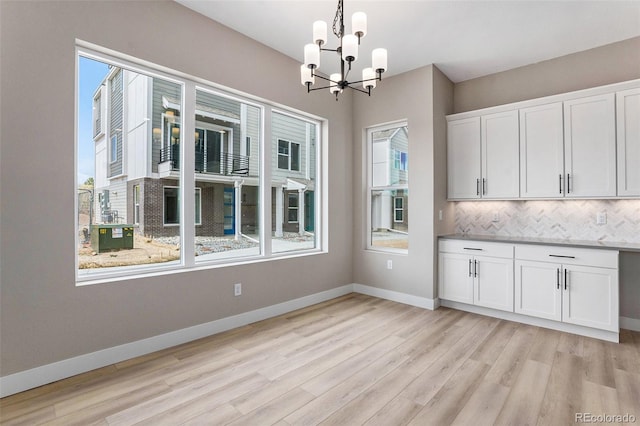 kitchen featuring pendant lighting, a chandelier, a healthy amount of sunlight, and white cabinets