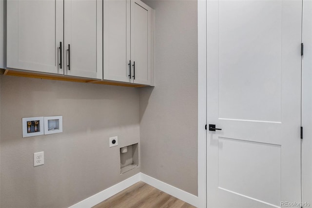 clothes washing area with hookup for a washing machine, light hardwood / wood-style floors, electric dryer hookup, and cabinets