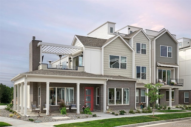 888 S Valentia St Unit 106, Denver, CO 80247 - view of property with a balcony, brick siding, a patio area, and roof with shingles