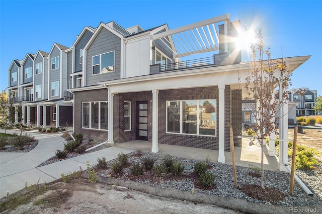 view of front of house featuring a residential view, brick siding, a porch, and a balcony