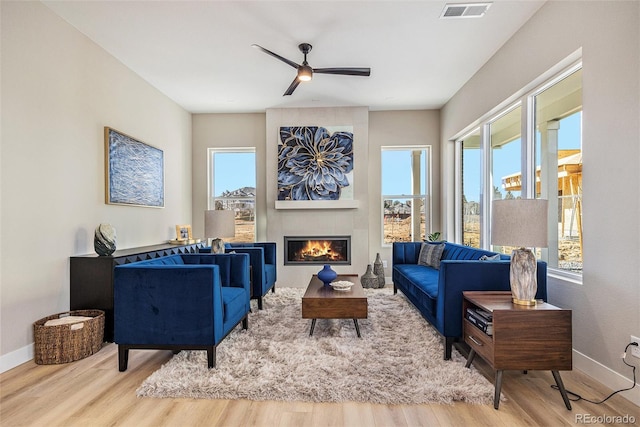 living area featuring a wealth of natural light, visible vents, and wood finished floors