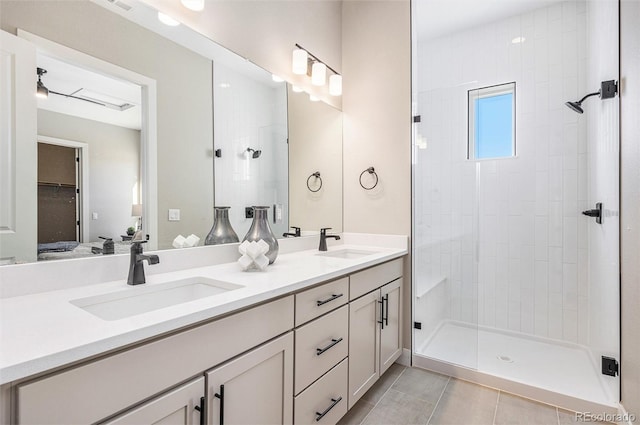 bathroom featuring double vanity, tile patterned flooring, a shower stall, and a sink