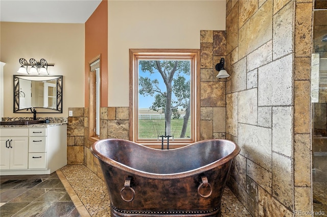 31200 E 145th Ave, Brighton, CO 80603 - bathroom featuring tile walls, stone tile floors, vanity, and a freestanding tub