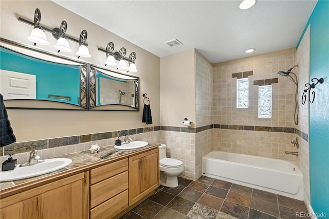 31200 E 145th Ave, Brighton, CO 80603 - bathroom with double vanity, shower / bath combination, tile walls, recessed lighting, and stone finish floors