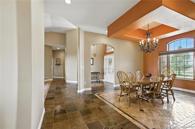 31200 E 145th Ave, Brighton, CO 80603 - dining space featuring arched walkways, stone tile floors, recessed lighting, a chandelier, and a towering ceiling