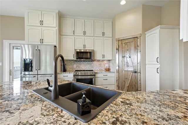31200 E 145th Ave, Brighton, CO 80603 - kitchen featuring appliances with stainless steel finishes, backsplash, light stone counters, and white cabinets
