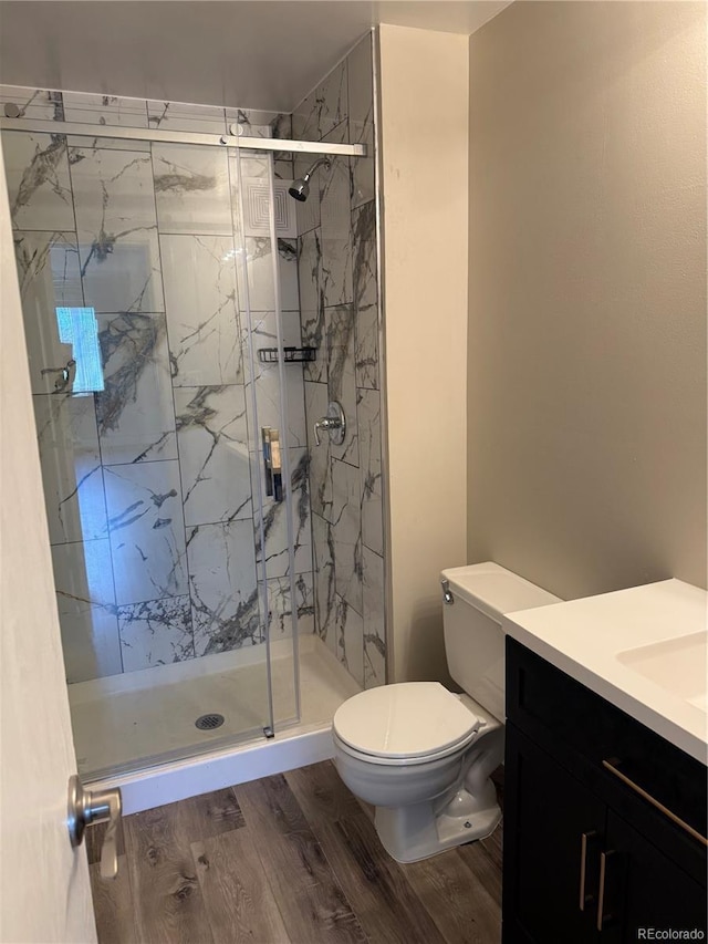 full bath featuring vanity, a marble finish shower, wood finished floors, and toilet