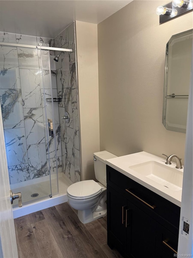 full bathroom featuring vanity, a marble finish shower, wood finished floors, and toilet