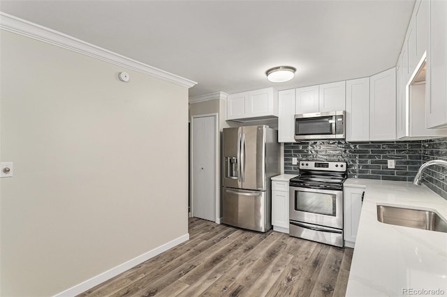 3460 S Poplar St Unit 404, Denver, CO 80224 - kitchen with appliances with stainless steel finishes, a sink, crown molding, decorative backsplash, and white cabinetry
