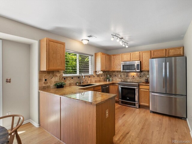 2548 Foothills Canyon Ct, Highlands Ranch, CO 80129 - kitchen with appliances with stainless steel finishes, a peninsula, light stone countertops, backsplash, and light wood-type flooring