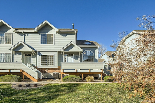 rear view of house featuring central AC unit and a lawn