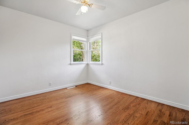 spare room featuring baseboards, wood finished floors, and ceiling fan