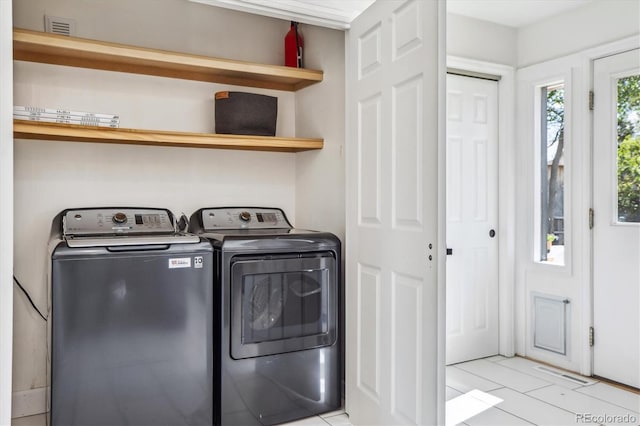 clothes washing area with independent washer and dryer and light tile patterned floors