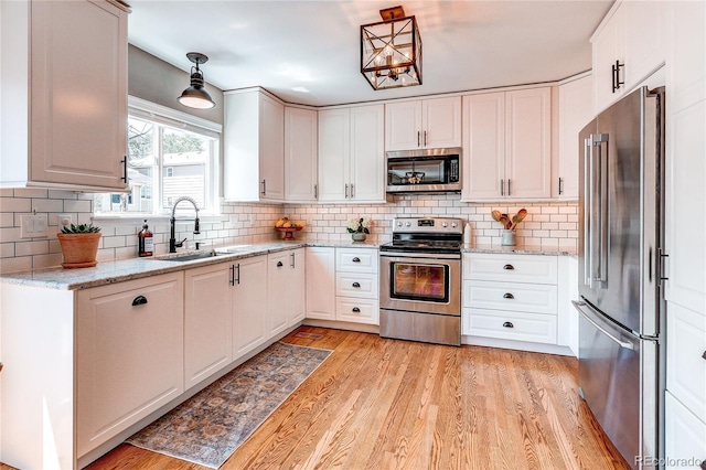 5397 S Killarney St, Centennial, CO 80015 - kitchen featuring appliances with stainless steel finishes, white cabinetry, light wood-style floors, decorative backsplash, and light stone counters