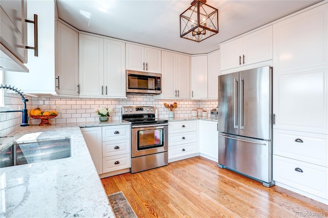 5397 S Killarney St, Centennial, CO 80015 - kitchen with appliances with stainless steel finishes, white cabinets, decorative backsplash, and light wood-type flooring
