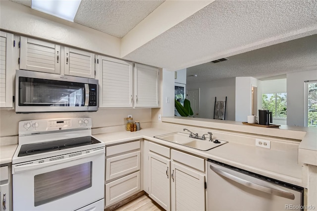 kitchen featuring white cabinetry, sink, stainless steel appliances, a textured ceiling, and light wood-type flooring