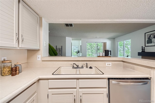 kitchen featuring white cabinets, a textured ceiling, stainless steel dishwasher, and sink