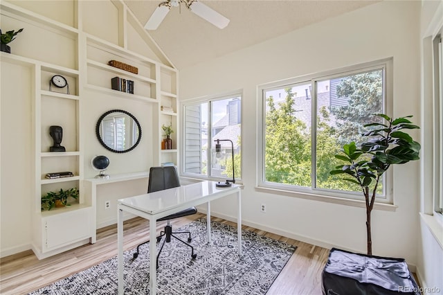 office space with a healthy amount of sunlight, lofted ceiling, and light hardwood / wood-style floors