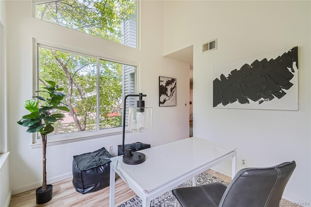 home office featuring a high ceiling and light wood-type flooring