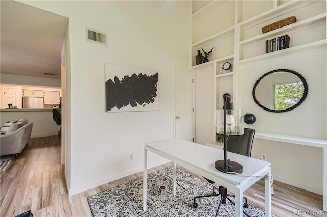 office area with light hardwood / wood-style floors and a textured ceiling