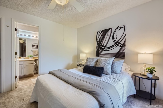 bedroom featuring ensuite bathroom, ceiling fan, light carpet, and a textured ceiling