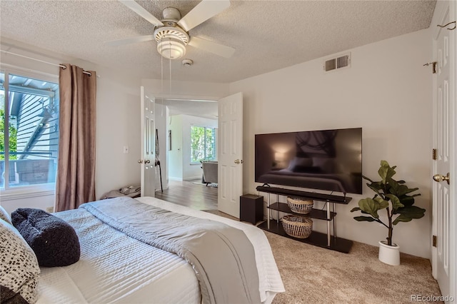 bedroom with a textured ceiling, carpet floors, and ceiling fan