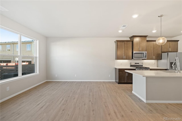 kitchen featuring hanging light fixtures, decorative backsplash, light hardwood / wood-style flooring, and stainless steel appliances