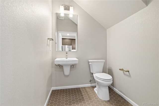 bathroom featuring tile patterned flooring, lofted ceiling, and toilet