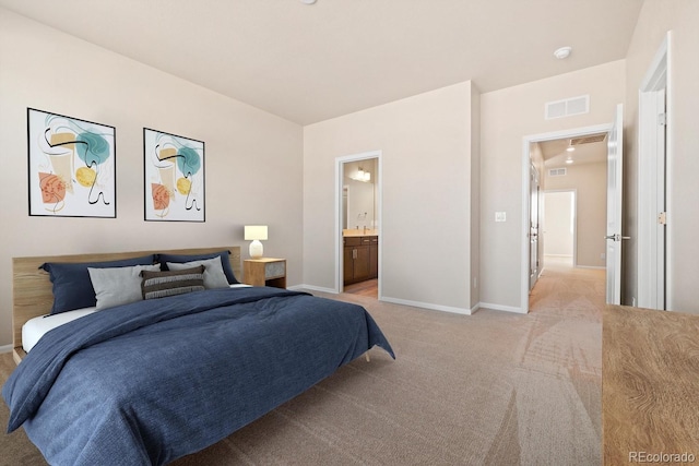 bedroom with ensuite bath and light carpet