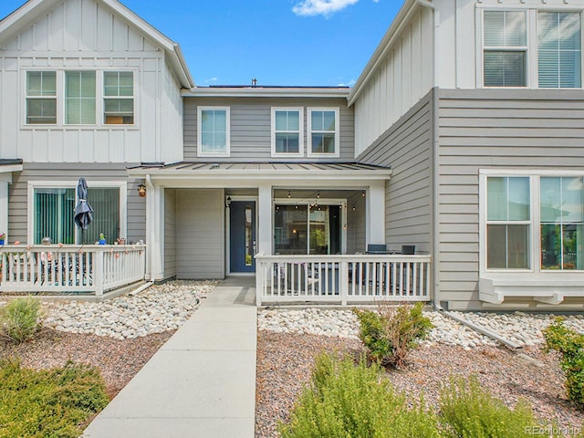 7488 W Pacific Ln, Denver, CO 80227 - view of front of home with board and batten siding, a porch, a standing seam roof, and a metal roof