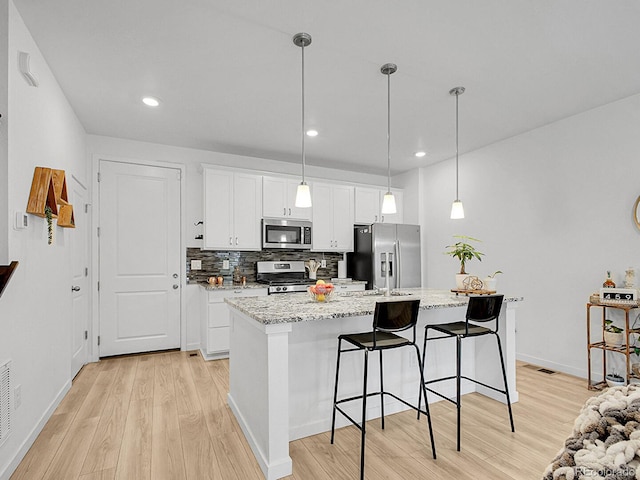7488 W Pacific Ln, Denver, CO 80227 - kitchen featuring appliances with stainless steel finishes, light wood finished floors, backsplash, white cabinets, and recessed lighting