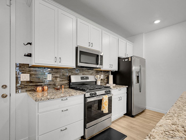 7488 W Pacific Ln, Denver, CO 80227 - kitchen featuring appliances with stainless steel finishes, light wood finished floors, tasteful backsplash, white cabinetry, and recessed lighting