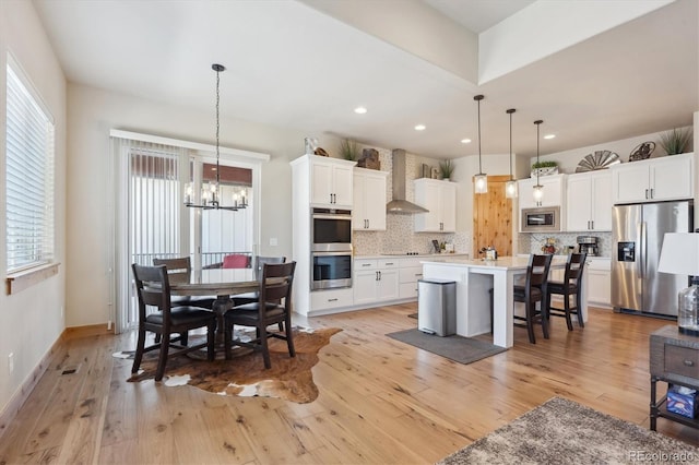 dining area with a healthy amount of sunlight, a chandelier, and light wood-type flooring