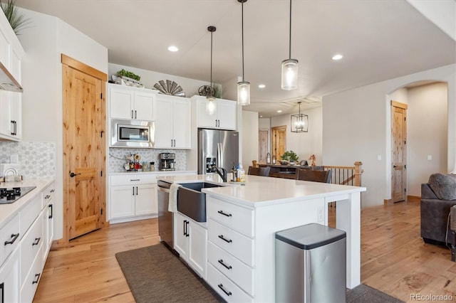 kitchen featuring white cabinetry, decorative backsplash, stainless steel appliances, and an island with sink