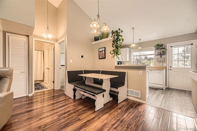 dining area featuring dark wood-type flooring, visible vents, and high vaulted ceiling