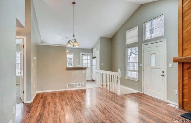 entryway with a notable chandelier, high vaulted ceiling, baseboards, wood finished floors, and visible vents
