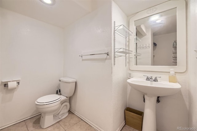 half bath with tile patterned flooring, baseboards, and toilet