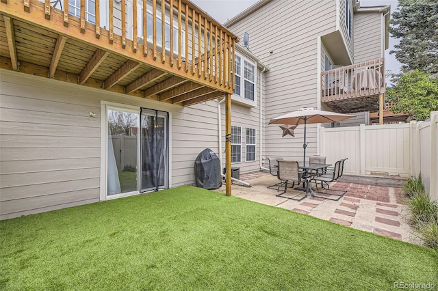 rear view of property featuring a yard, fence, a balcony, and a patio area