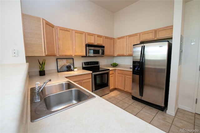 kitchen with light brown cabinetry, sink, light tile patterned floors, and appliances with stainless steel finishes