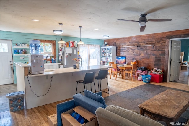 living room with ceiling fan, hardwood / wood-style flooring, and wood walls