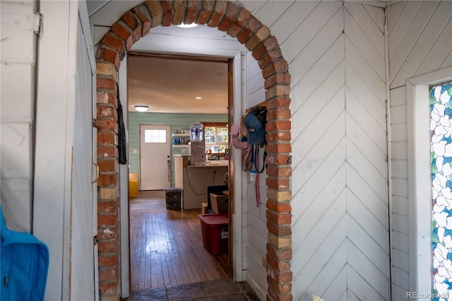 hall with hardwood / wood-style flooring and wood walls