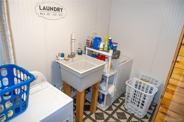 laundry area featuring wood walls, washer and dryer, and sink