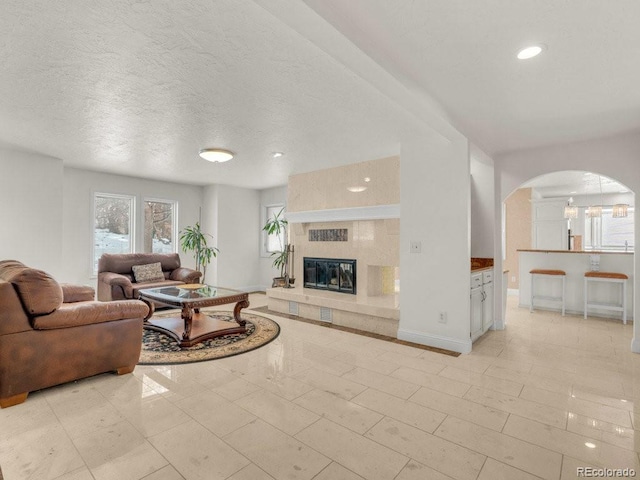 living room featuring a tiled fireplace and a textured ceiling