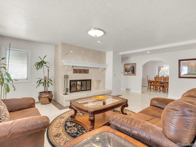 living room featuring a textured ceiling, a premium fireplace, and a healthy amount of sunlight