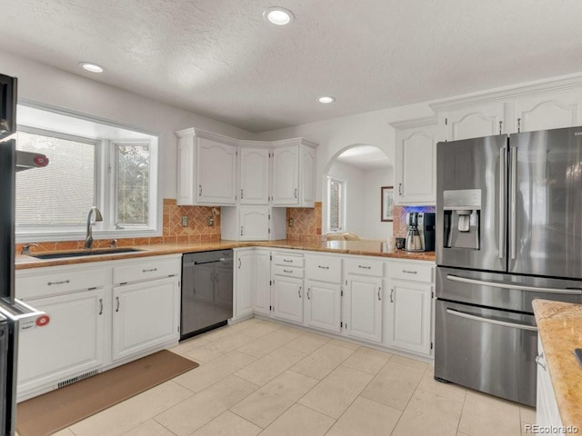 kitchen with sink, stainless steel fridge, white cabinets, and black dishwasher