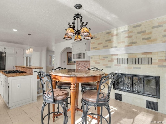 kitchen with white cabinetry, tasteful backsplash, a center island, hanging light fixtures, and light tile patterned floors