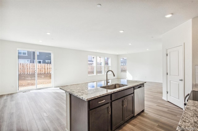 kitchen with dishwasher, sink, light stone counters, dark brown cabinetry, and light hardwood / wood-style floors