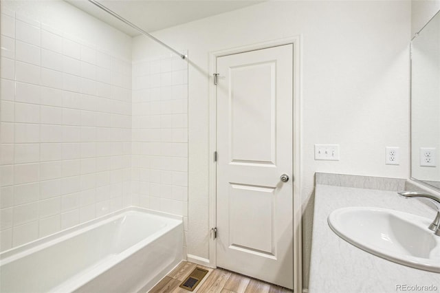 bathroom with tiled shower / bath, hardwood / wood-style floors, and vanity