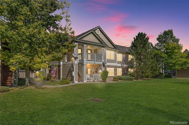 view of front facade featuring stairs, a yard, stone siding, and a balcony