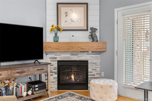 living room with a lit fireplace and wood finished floors